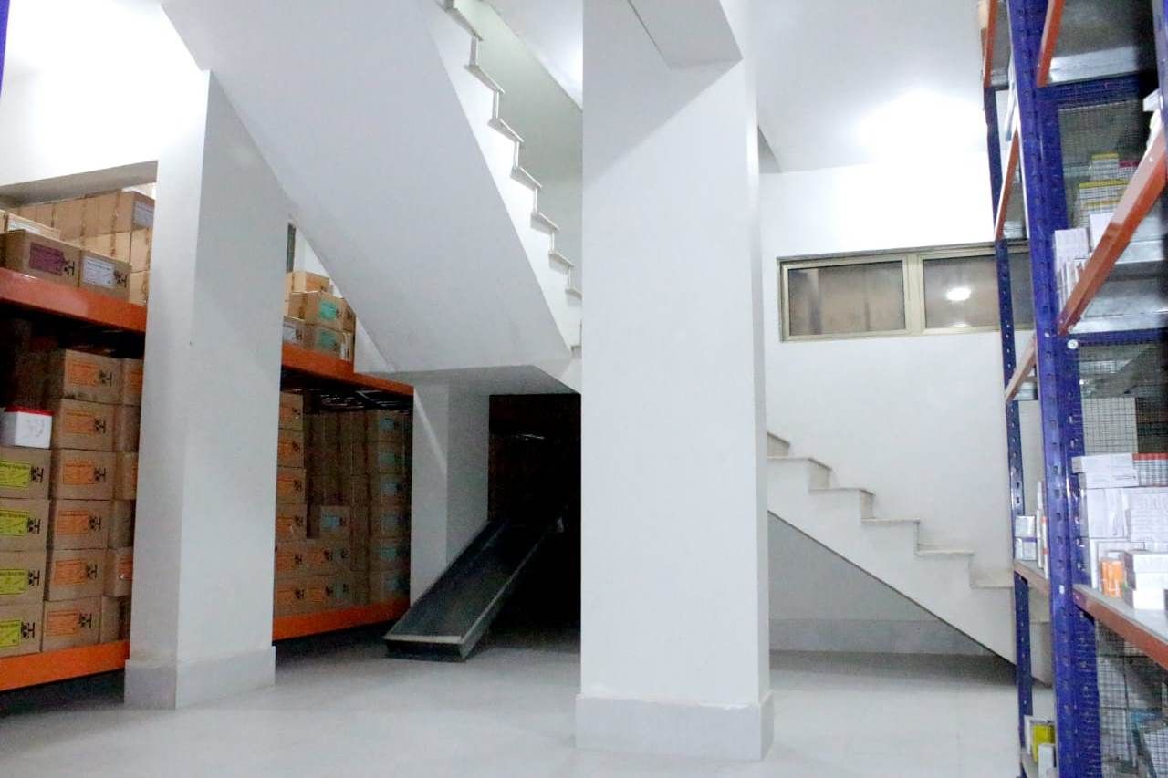 Clean warehouse hall with racking, shelving and a staircase to the upper level