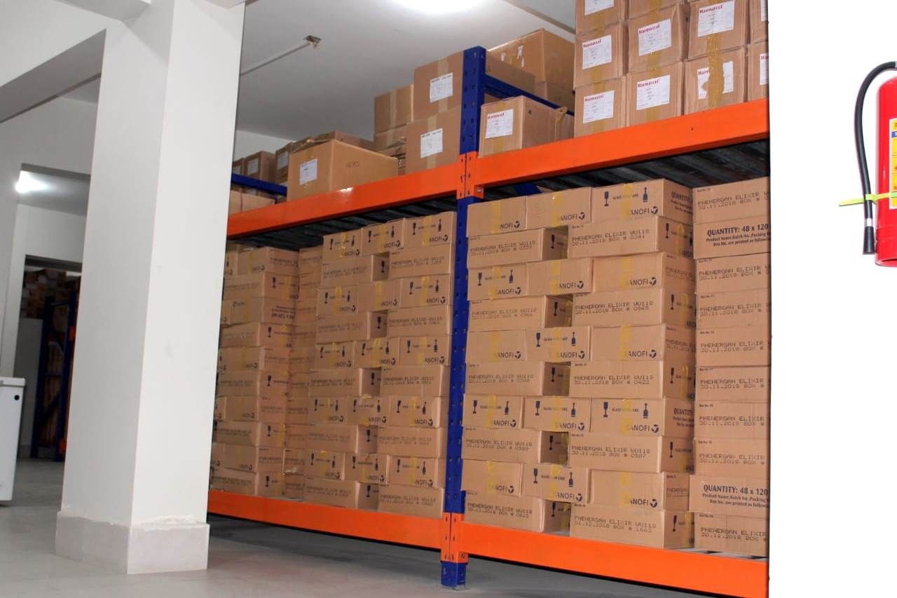 Warehouse racking with labelled cartons beside a wall-mounted fire extinguisher